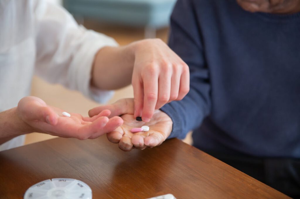 pexels photo 7551633 Close-up of hands passing medicine, symbolizing care and support in a nursing home.